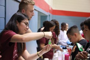 student stirring a green substance in a jar